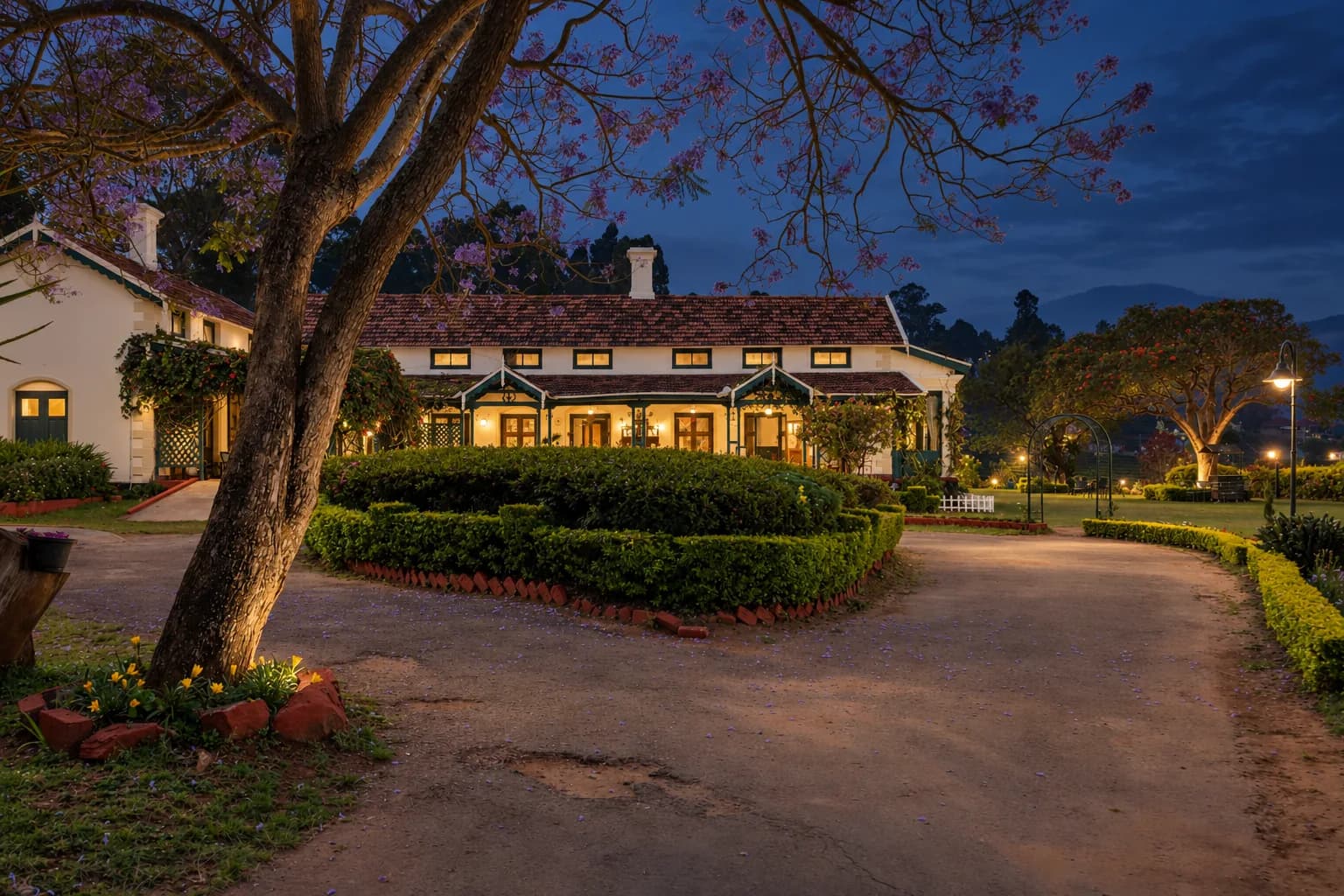 The house at dusk, windows lit along the drive