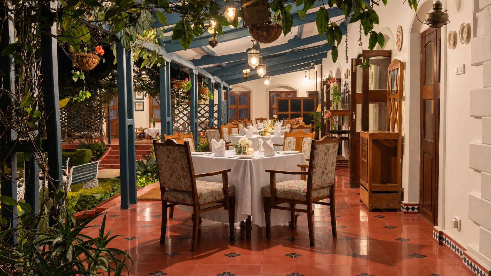 A table laid on the covered terrace, lanterns overhead