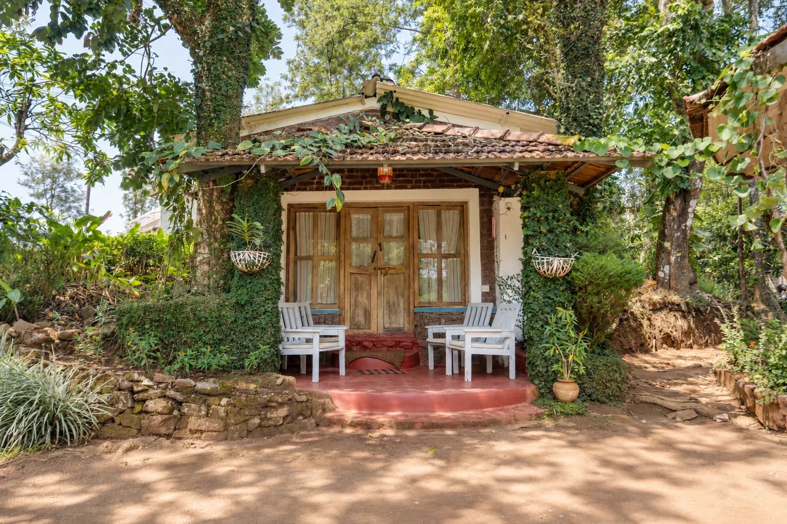 A creeper-covered cottage with a red veranda and two chairs