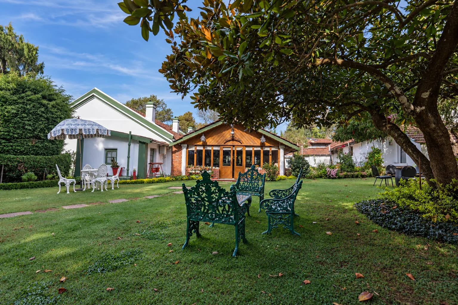 Green garden benches under the tree, the house beyond