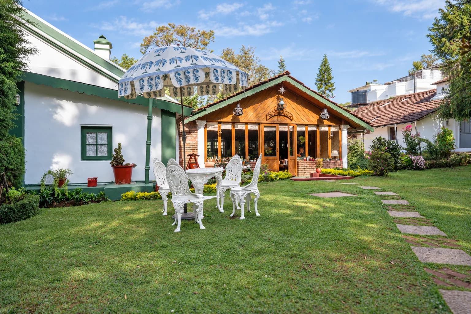 A parasol and white garden chairs in front of the veranda
