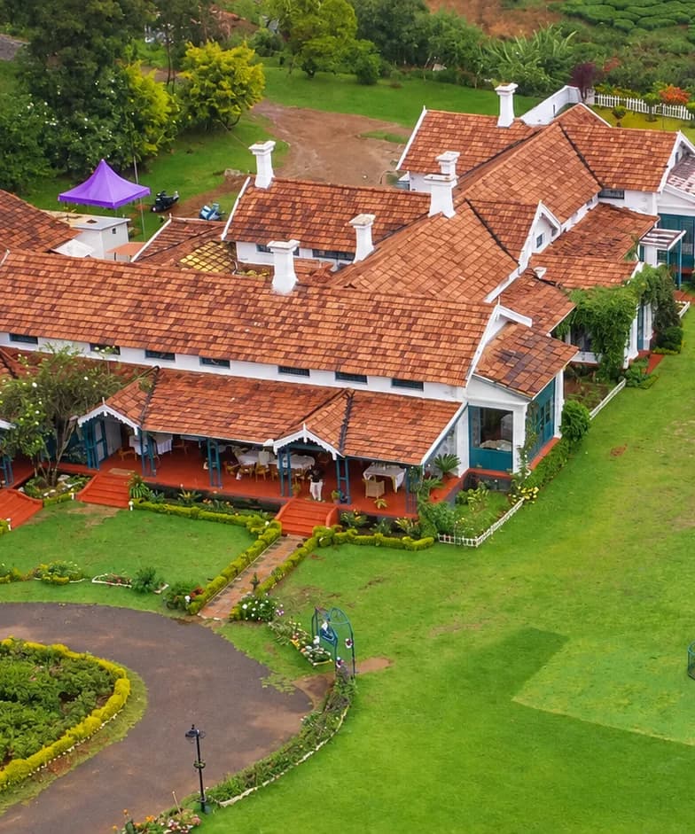 180° McIver from the air, its tiled roofs and long veranda above the lawn and tea slopes